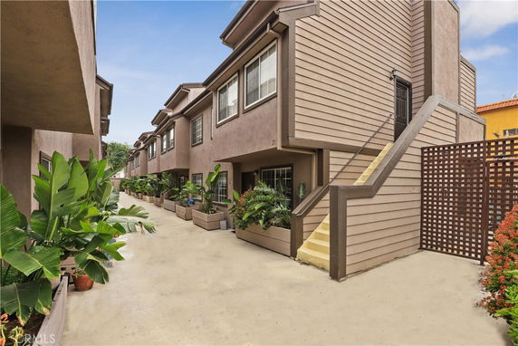 Front view of adjacent townhouses with stairs and vegetation.