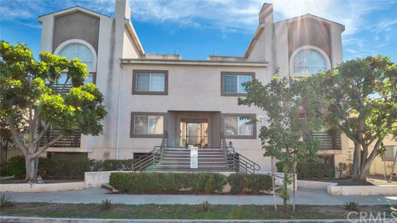 Front view of a multi-story residential building with stairs leading to the entrance.
