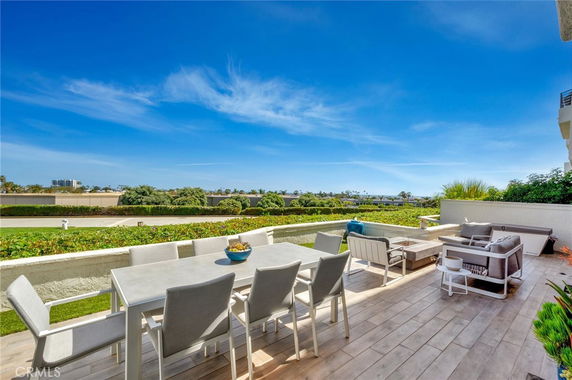 Outdoor patio area with seating and a dining table overlooking greenery.