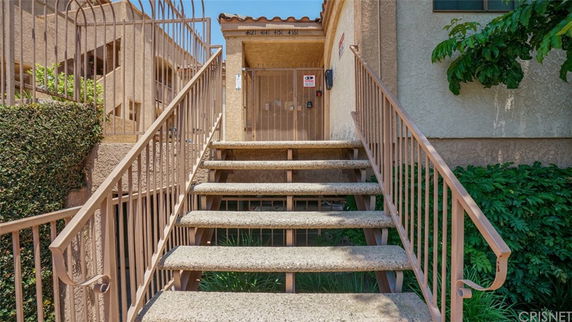 Front view of a building entrance with stairs and railings leading up to a gate.