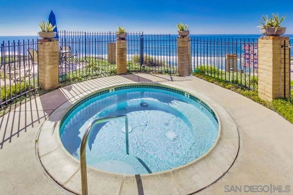 Small circular outdoor pool with ocean view and surrounding rail fence.