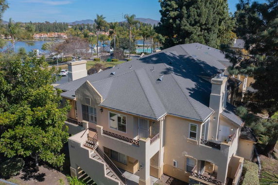 Aerial view of a multi-story house with a complex roof structure near a body of water.