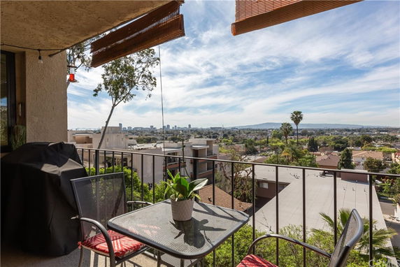 Panoramic view from a balcony overlooking a cityscape with buildings and trees.