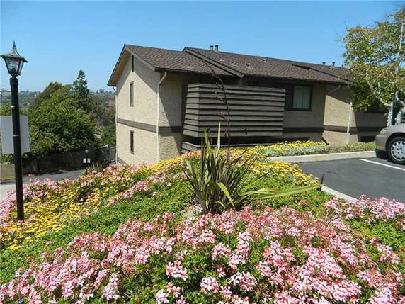 Side view of a two-story house with brown roof and beige siding.