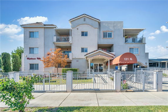 Front view of a three-story apartment building with balconies and a gated entrance.
