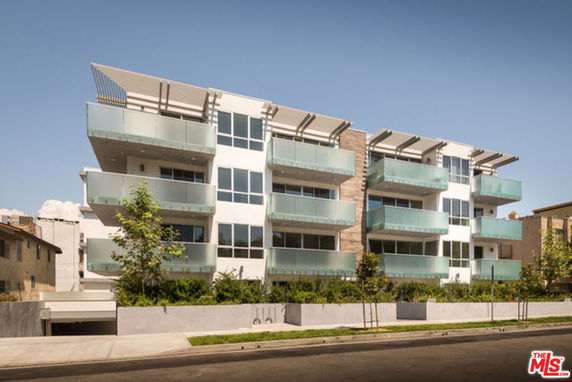 Front view of a modern multi-story apartment building with glass balconies.