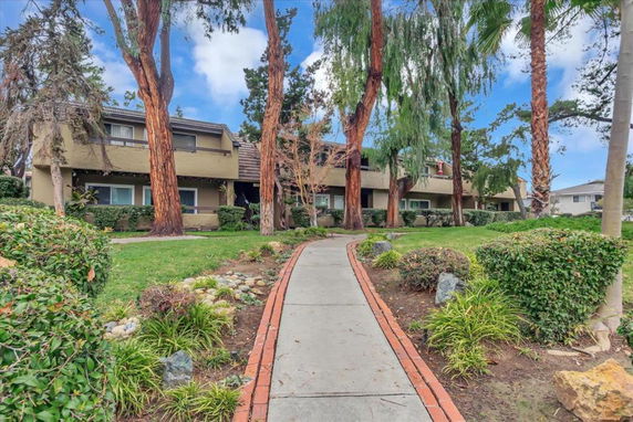 Front view of a two-story residential building with trees and a walkway.