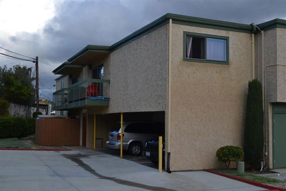 Two-story building with an overhang and parking space underneath.