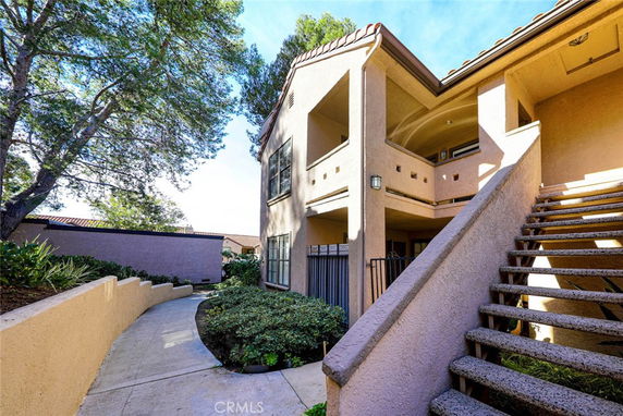 Front view of a multi-level building with outdoor staircase and walkway.