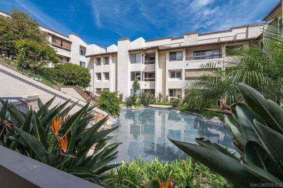 Front view of a multi-story building with a swimming pool and surrounding vegetation.