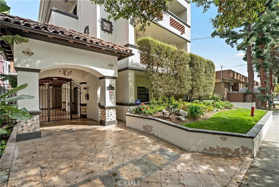 Front view of a multi-story residential building with an arched entrance and tiled roof.