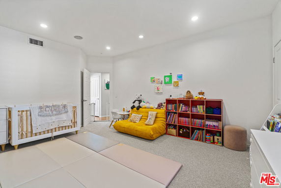 Room with a play mat, small bookshelf, and toys for children.