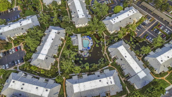 Aerial view of an apartment complex with parking areas and green spaces.