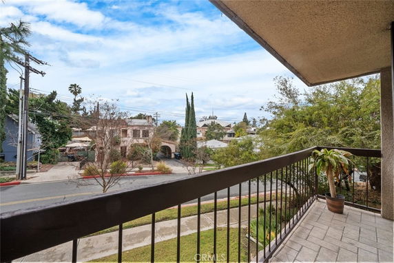 View from a balcony showing surrounding residential area with trees and houses.