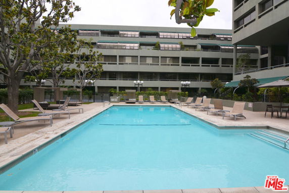 Outdoor swimming pool area with lounge chairs and surrounding building.
