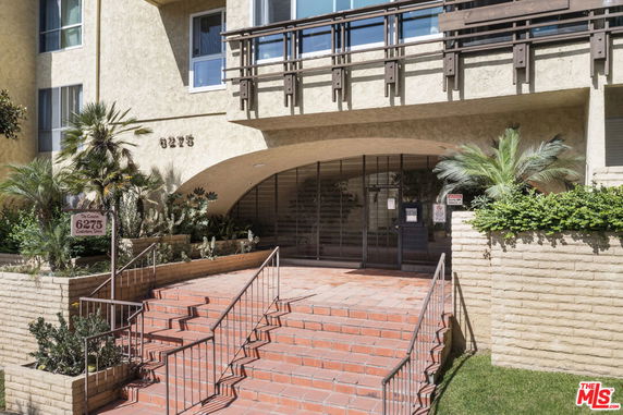 Front view of a residential building with a gated entrance and stairs.