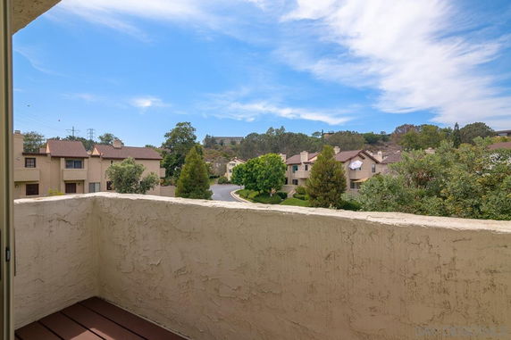 Panoramic view from a balcony overlooking a residential area with multiple houses and trees.