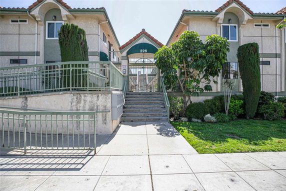 Front view of a multi-story residential building with stairs and a pathway leading up to the entrance.