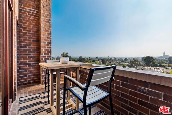 View from a brick balcony with table and chairs overlooking surrounding areas.