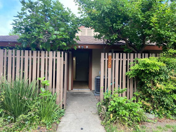 Front view of a house with a wooden fence and plants.