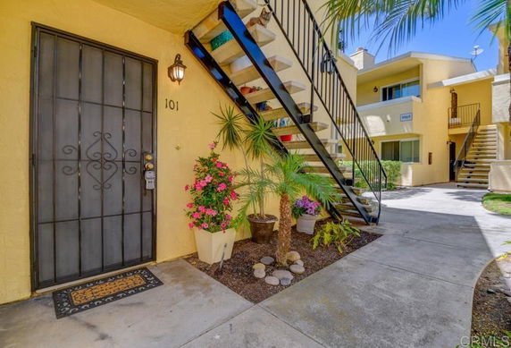Front view of an apartment building with stairs and potted plants.