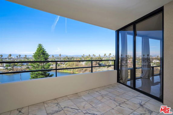 Wide angle view from a balcony overlooking a landscape with trees and buildings.
