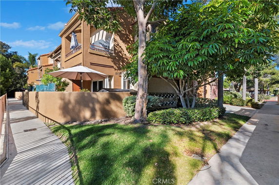 Front view of a multi-story house with outdoor patio and umbrella.