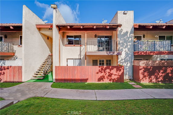 Front view of a two-story apartment building with balconies and a shared staircase.