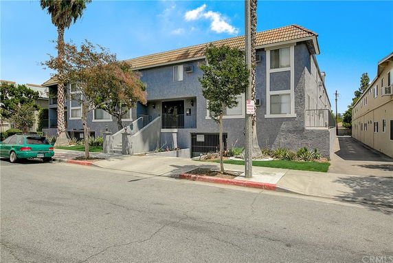 Front view of a two-story residential building with a tiled roof and external staircase.