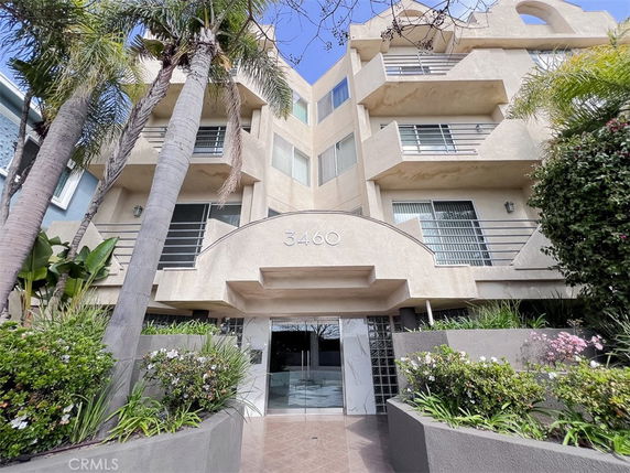 Front view of a multi-story building with balconies and glass entrance.