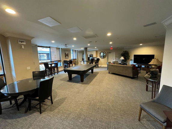 Room with pool table, seating area, and large TV.