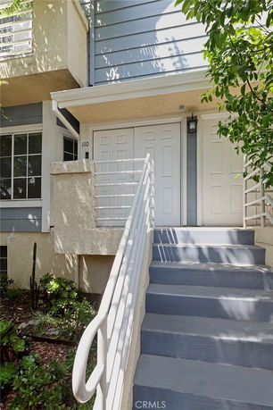 Front view of a house with a small porch and staircase leading to the entrance.