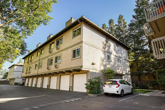 Front view of a multi-story residential building with garages on the ground floor.