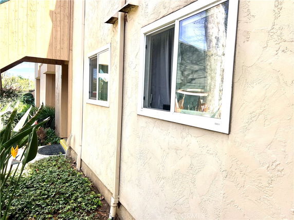 Side view of a building featuring windows and stucco exterior walls.