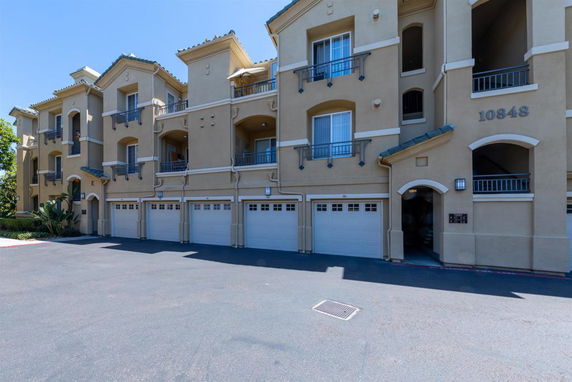 Front view of a multi-story building with multiple garages on the ground level.