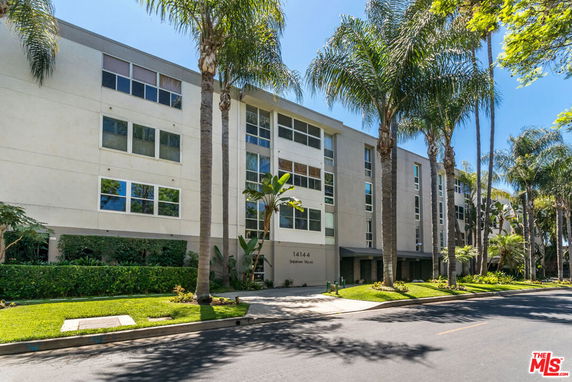 Front view of a multi-story building with large windows and palm trees.