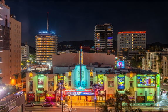 Front view of a colorful multi-story building with bright lights at night.