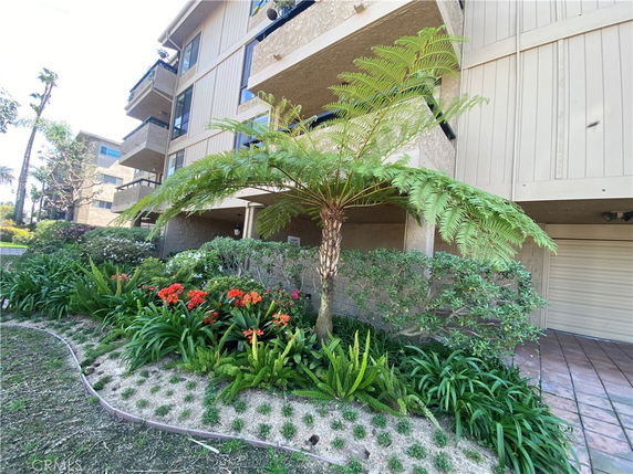 Front view of a multi-story building with balconies and landscaped garden.