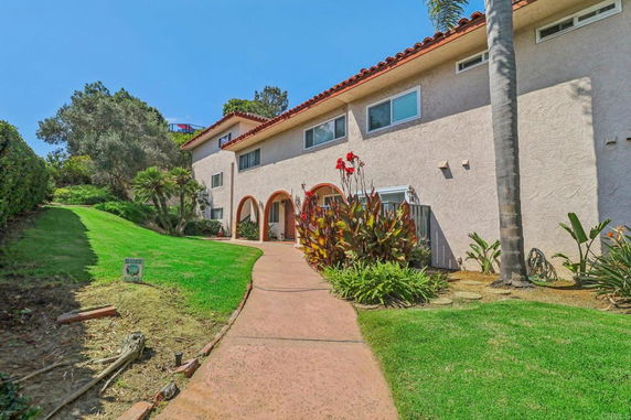 Front view of a two-story house with arched entryway and tiled roof.