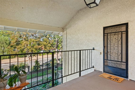 Front view from a balcony overlooking trees and street.