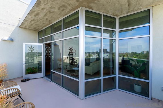 Modern rooftop patio with large glass windows and seating area.