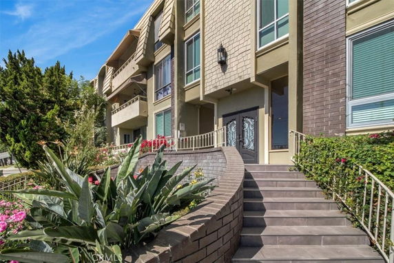 Front view of a multi-story building with a staircase entrance and landscaped surroundings.