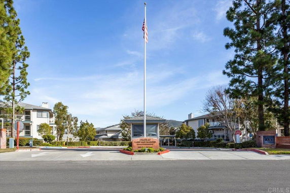 Front view of a residential building with an entrance sign and flagpole.