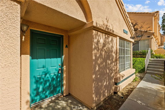 Front view of a house entrance with a green door and adjacent window.