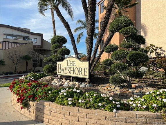 Front view of a building with a sign that reads 'The Bayshore' and landscaped shrubs and trees.