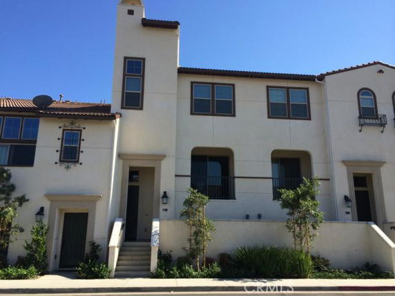 Front view of a multi-story townhouse with beige walls and red-tiled roof.