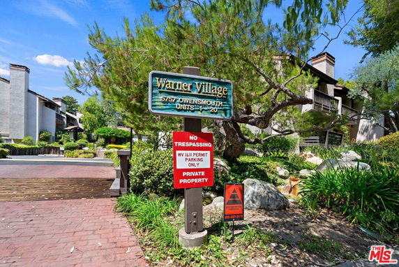 Front view of a residential complex with multiple-story buildings and a large sign at the entrance.