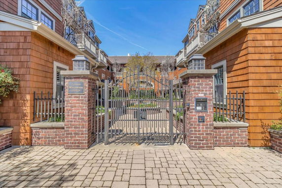 Front view of a multi-story building with a gated entrance and brick pillars.