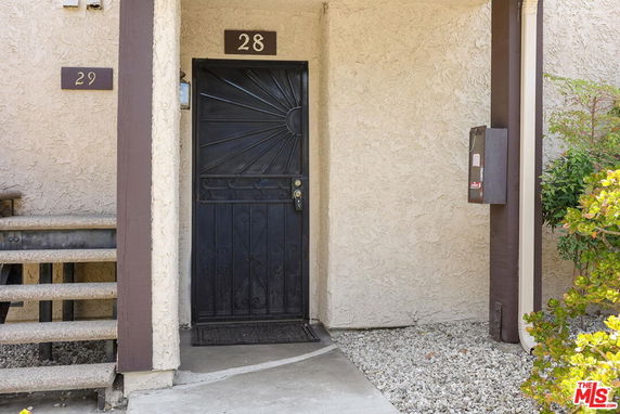 Front entrance view of a residential building with a black metal door and units numbered 28 and 29.