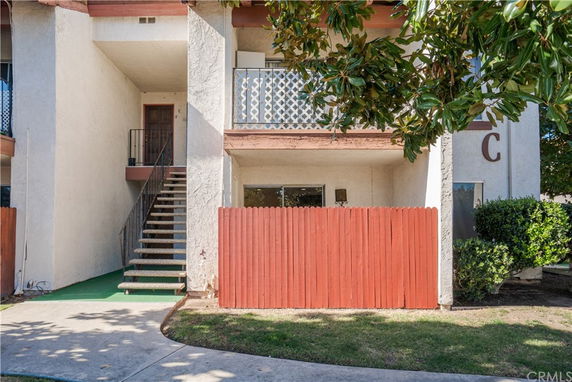 Front view of a two-story residential building with exterior staircase and balcony.